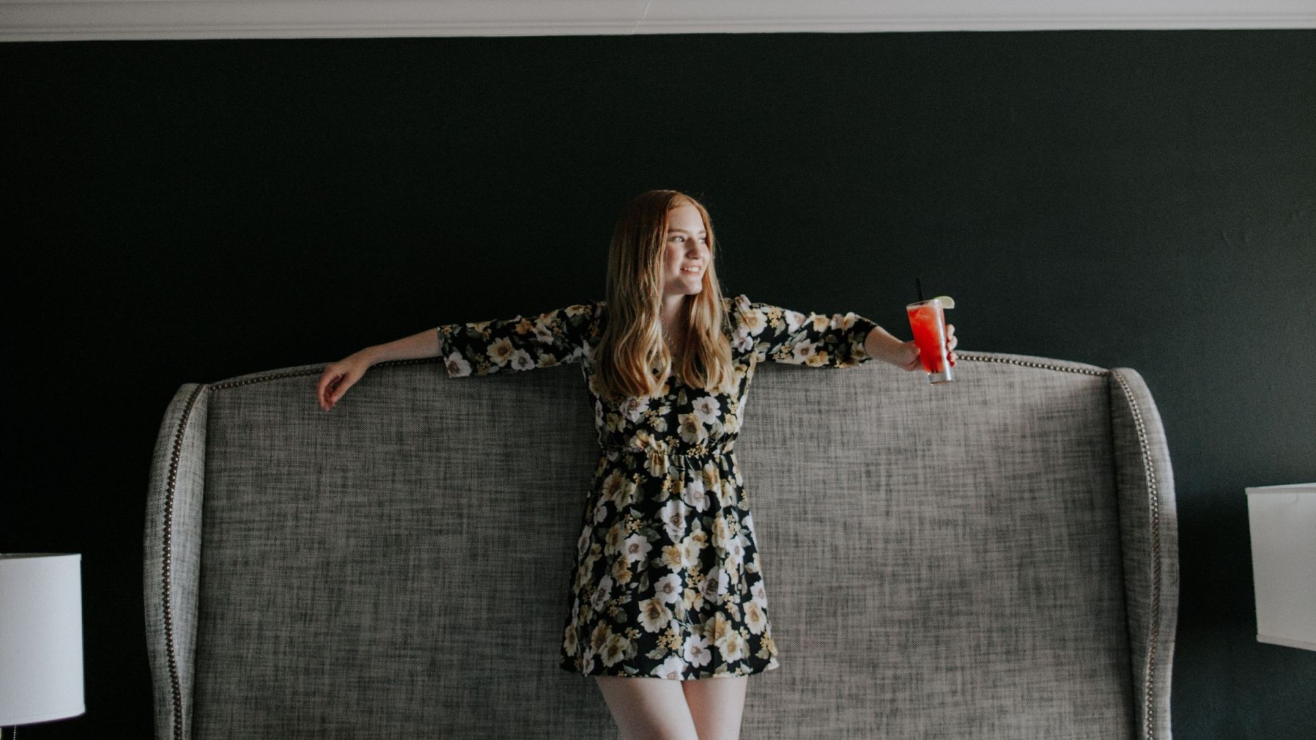 A Person In A Dress Holding A Red Cup And Standing On A Couch