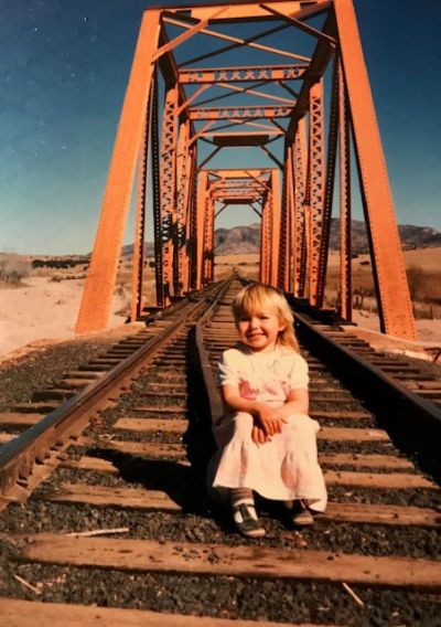 Little girl sitting on rail tracks